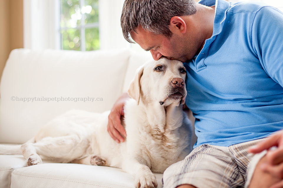 A man shares affection with his labrador retriever at home in Ontario, photo.