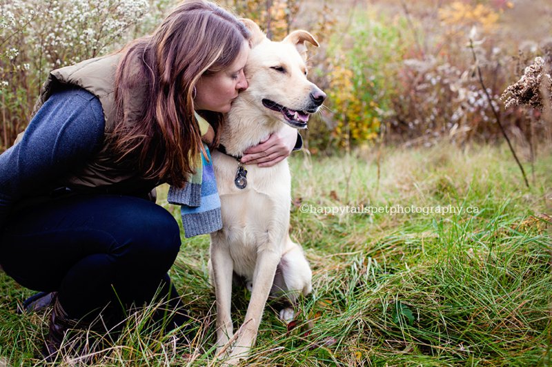 Woman and dog snuggle in rustic autumn field by Ontario people and pet photographer.