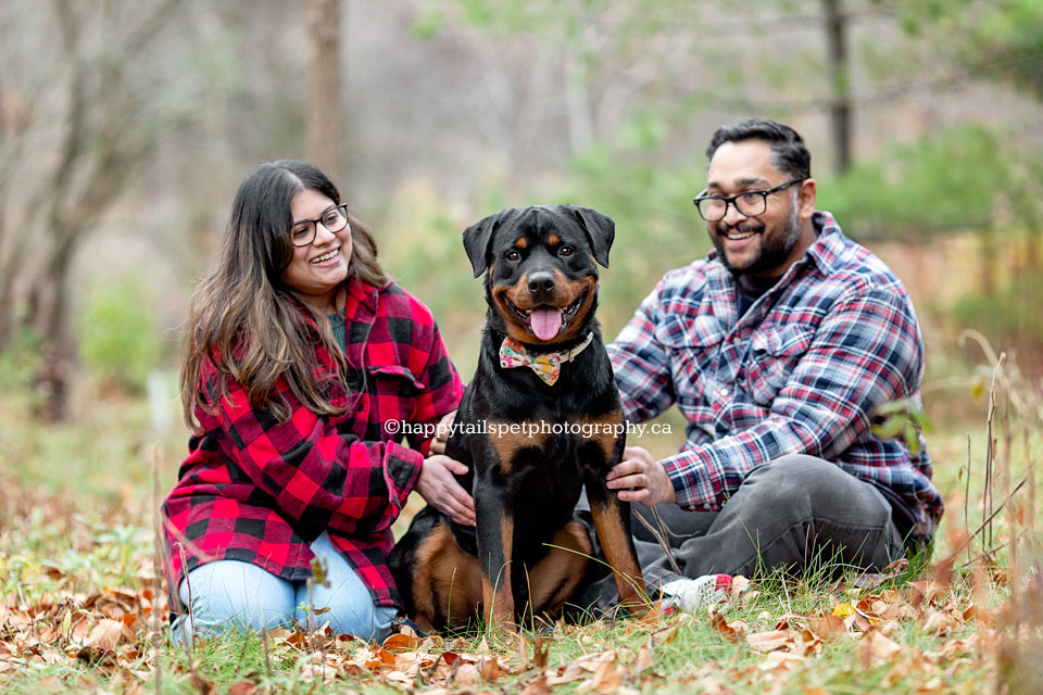 Couple in plaid coats with pet dog in Oakville forest.